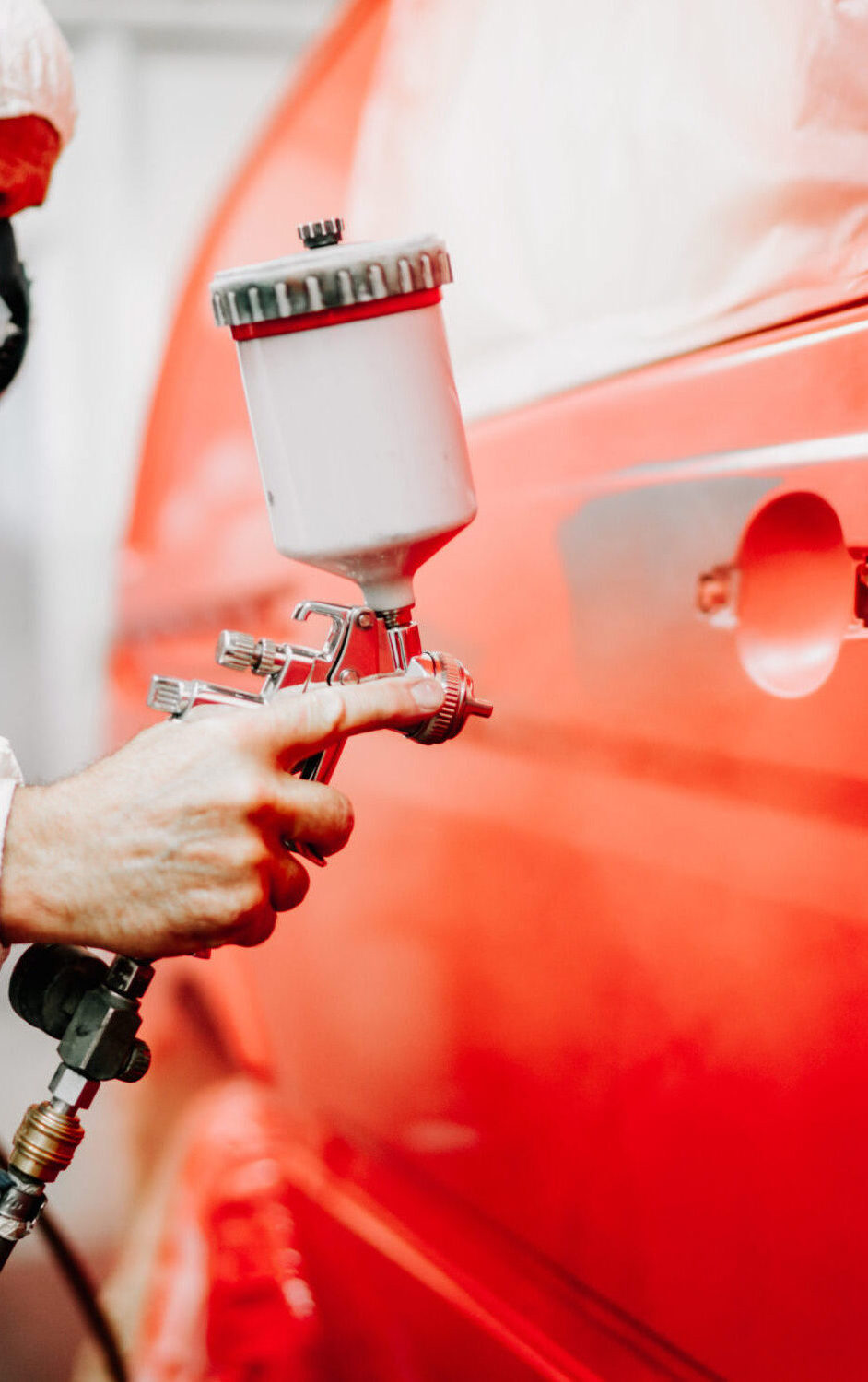 Close up details of mechanic worker, painting a red car