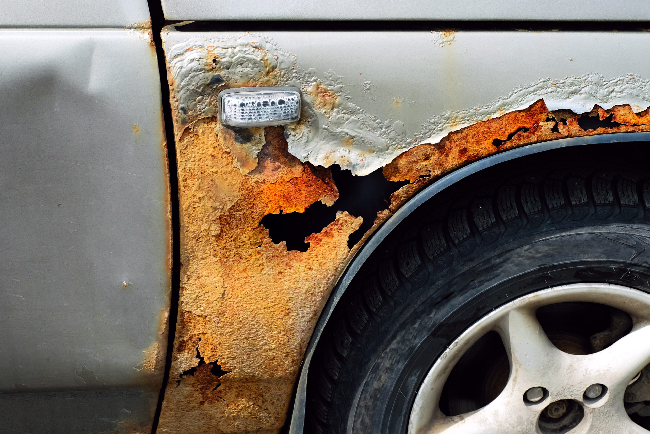 rust on the car. car wing with a hole.